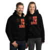 A man & a woman standing next to each other smiling. Both are wearing the black revolution hoodie.